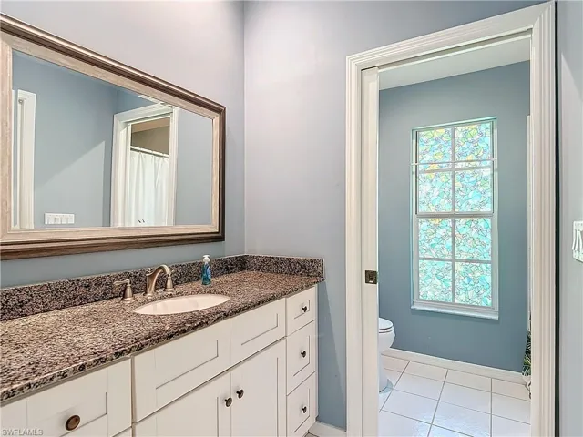 Bathroom with a wealth of natural light, tile flooring, vanity, and toilet
