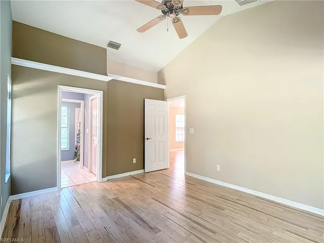 Spare room with high vaulted ceiling, ceiling fan, and light hardwood / wood-style flooring