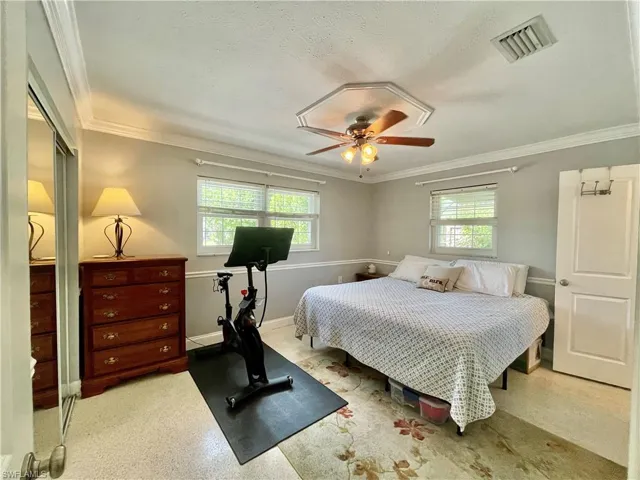 Bedroom featuring multiple windows, ceiling fan, and crown molding