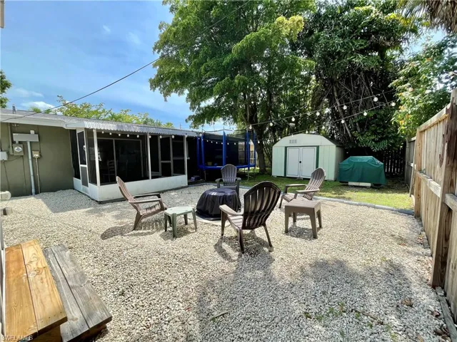 View of patio featuring a storage shed, a sunroom, an outdoor fire pit, and a grill