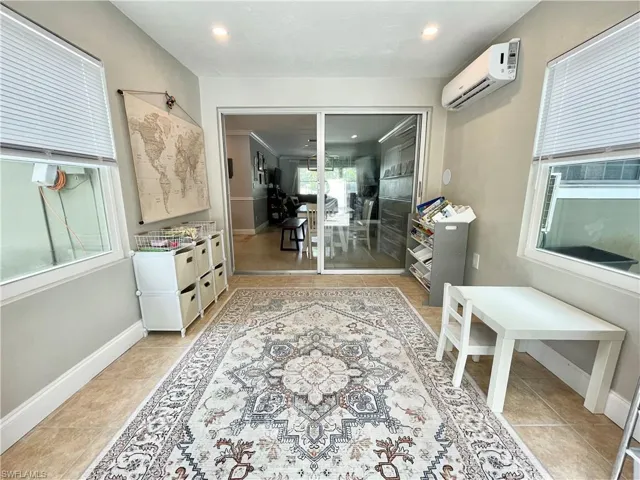 Living area featuring light tile patterned flooring and an AC wall unit