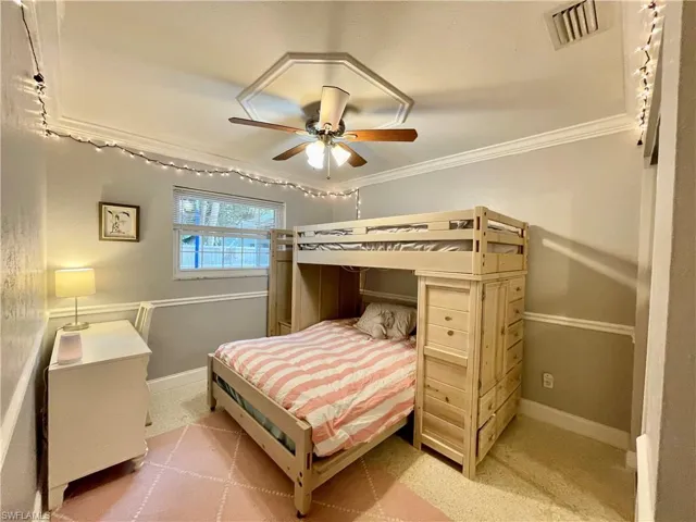 Bedroom featuring light carpet, ceiling fan, and ornamental molding