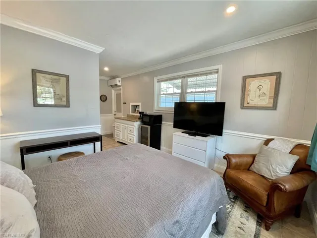 Bedroom with light tile patterned floors, an AC wall unit, and crown molding