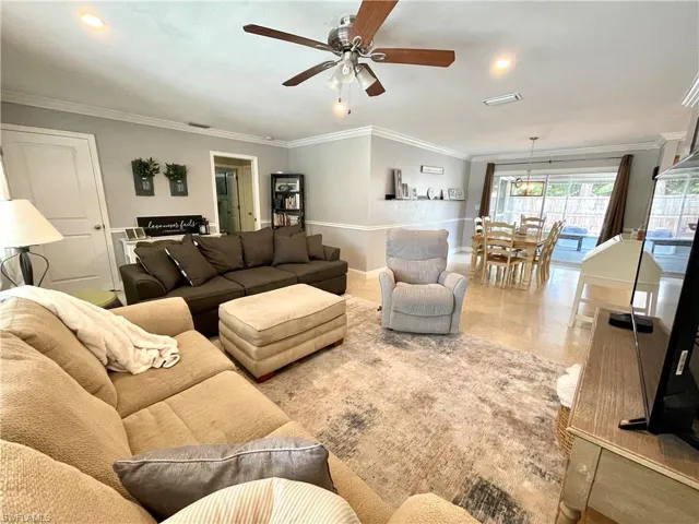 Tiled living room featuring crown molding and ceiling fan