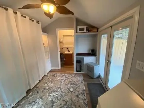 Bedroom with hardwood / wood-style flooring, ceiling fan, connected bathroom, and lofted ceiling