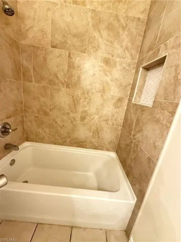 Bathroom with bathing tub / shower combination and tile patterned flooring