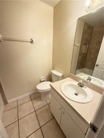 Bathroom featuring vanity, a textured wall, light tile patterned floors, and washtub / shower combination