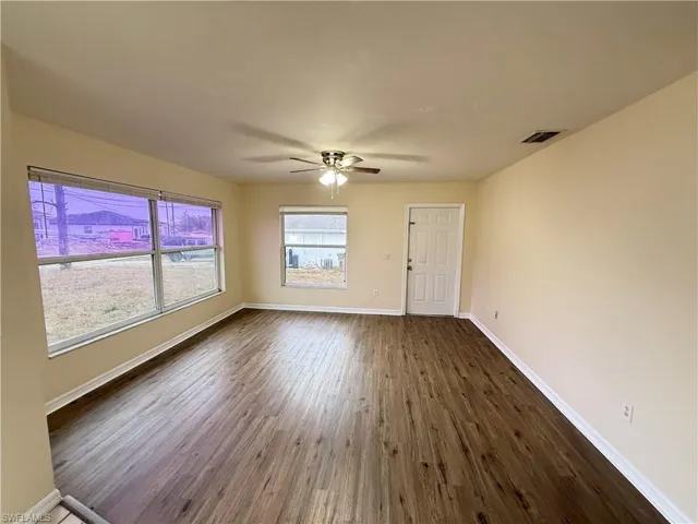 Unfurnished room featuring dark wood-style floors and ceiling fan