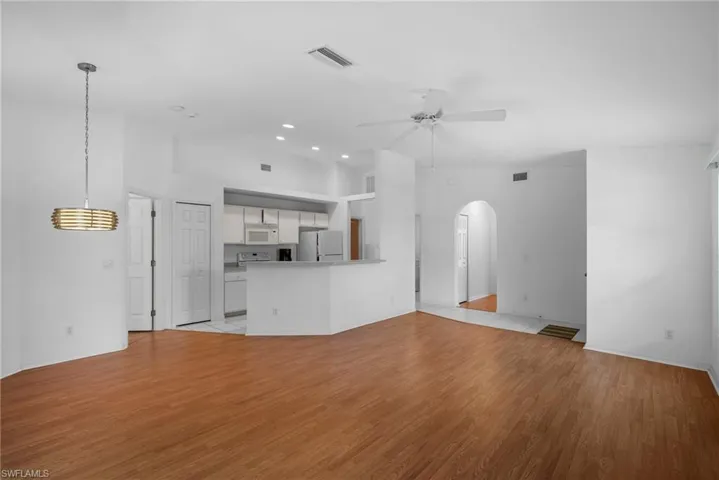 Unfurnished living room with light tile patterned flooring, high vaulted ceiling, and ceiling fan