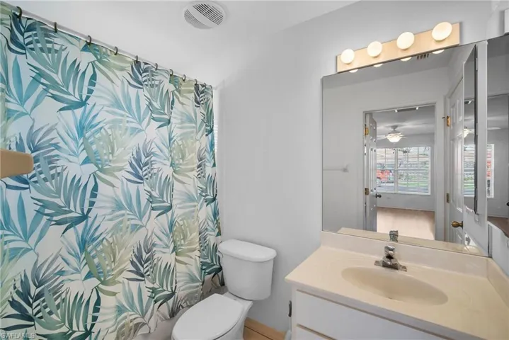 Bathroom with toilet, vanity, and ceiling fan