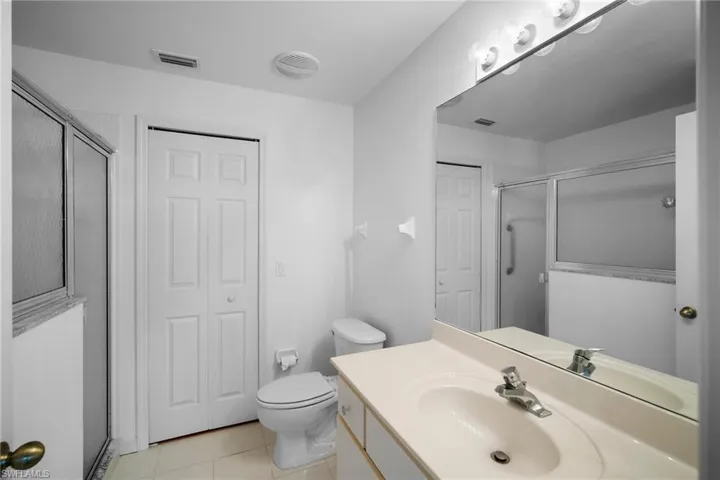Bathroom featuring vanity, toilet, tile patterned floors, and an enclosed shower