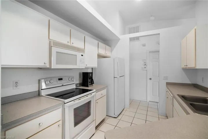 Kitchen featuring light tile patterned flooring, sink, and white appliances