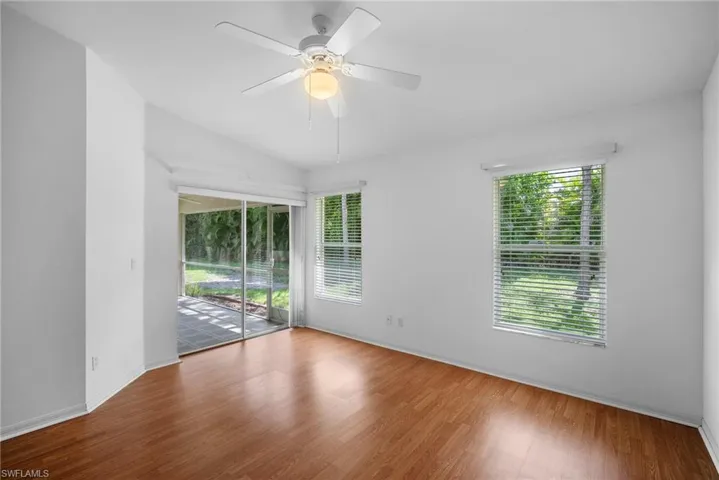 Empty room with wood-type flooring, ceiling fan, vaulted ceiling, and a healthy amount of sunlight