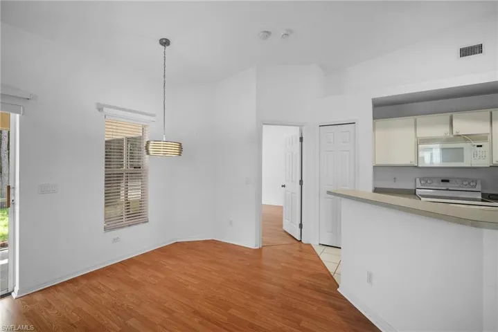 Kitchen featuring a wealth of natural light, hanging light fixtures, white appliances, and light wood-type flooring