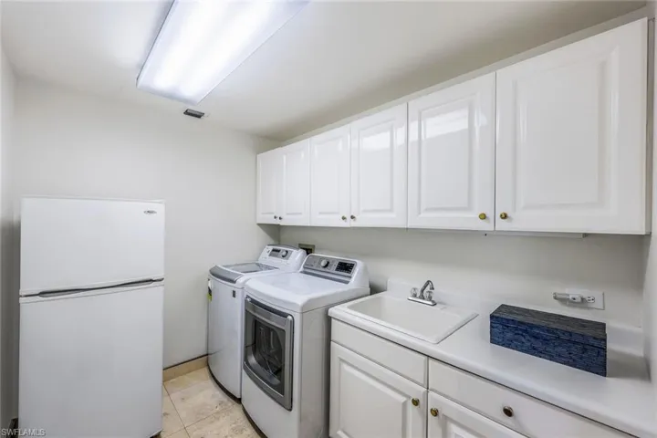 Laundry area featuring a washer, dryer, fridge, and sink.