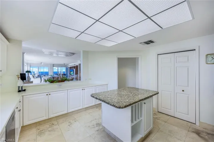 Kitchen with stainless steel appliances, white cabinets, sink, light tile patterned flooring, and a center island