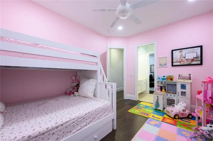 Bedroom with dark hardwood / wood-style floors, ceiling fan, and connected bathroom