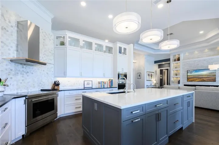 Kitchen featuring white cabinetry, dark wood-type flooring, appliances with stainless steel finishes, wall chimney exhaust hood, and sink