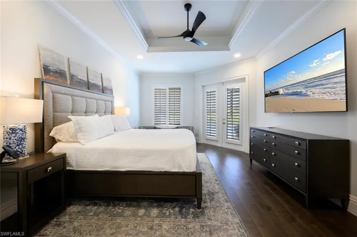 Bedroom with ceiling fan, ornamental molding, access to outside, a raised ceiling, and dark wood-type flooring