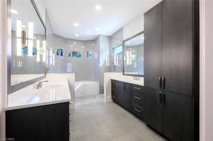 Bathroom with tiled bath, tile patterned floors, and vanity