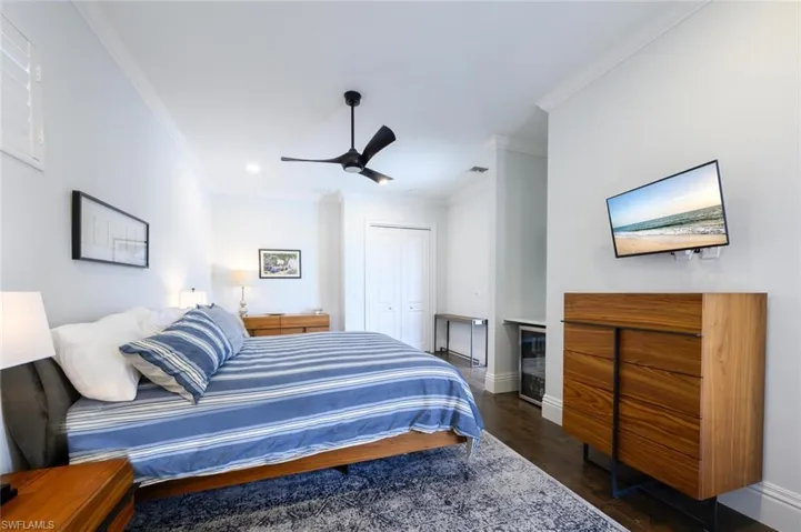 Bedroom with crown molding, dark hardwood / wood-style flooring, a closet, and ceiling fan