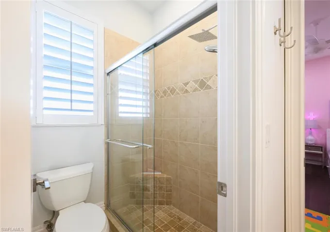 Bathroom featuring a shower with shower door and toilet