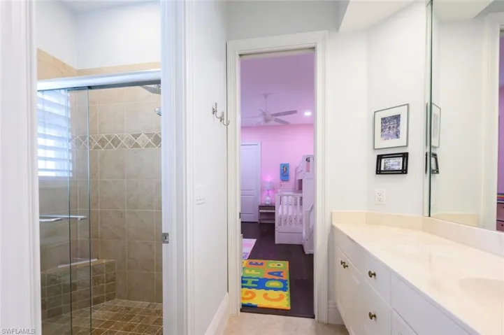 Bathroom featuring tile patterned flooring, a shower with shower door, vanity, and ceiling fan