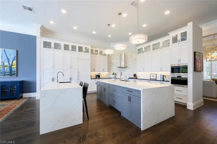 Kitchen with a breakfast bar area, white cabinets, backsplash, dark hardwood / wood-style floors, and a spacious island