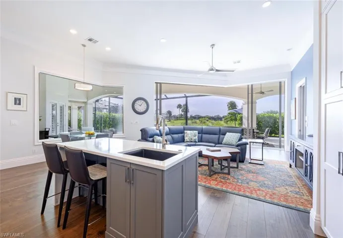 Kitchen featuring hanging light fixtures, sink, dark hardwood / wood-style floors, a center island with sink, and gray cabinetry
