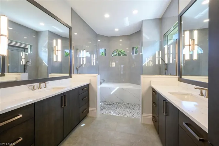 Bathroom with tiled tub, tile patterned flooring, plenty of natural light, and double vanity