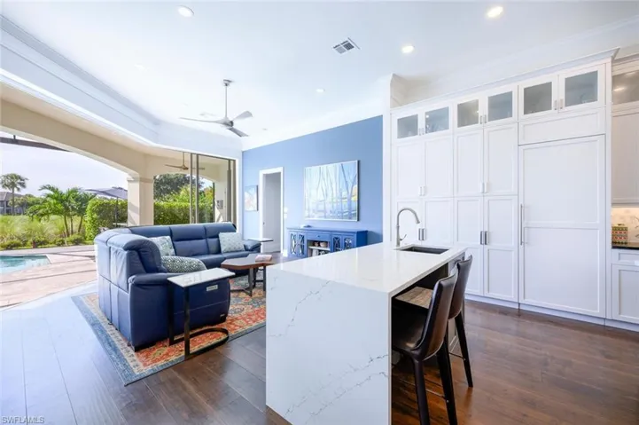 Kitchen featuring sink, light stone counters, a kitchen island with sink, dark wood-type flooring, and ceiling fan