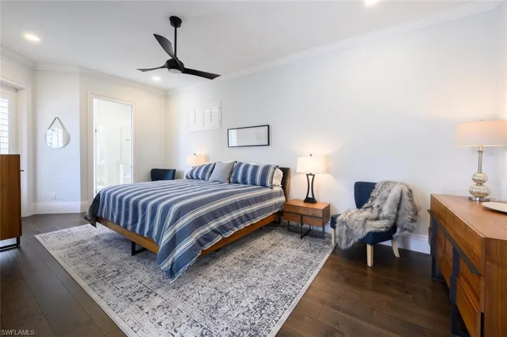 Bedroom featuring ensuite bath, ceiling fan, dark hardwood / wood-style flooring, and ornamental molding