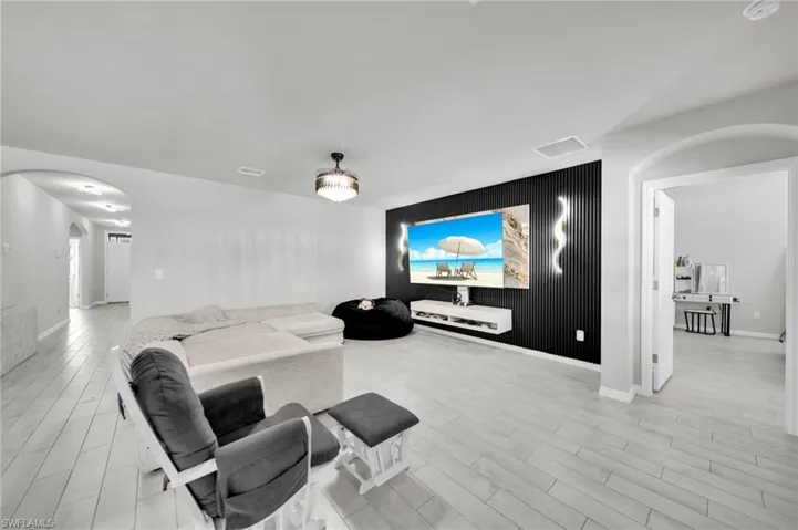 Cinema room featuring an accent wall, arched walkways, light wood-style flooring, and wood walls