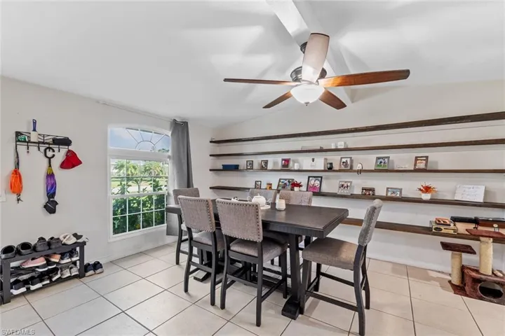 Dining space with light tile patterned floors, vaulted ceiling, and ceiling fan