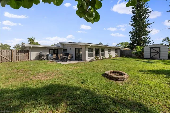 Back of property featuring a yard, a patio, a fire pit, and a storage shed