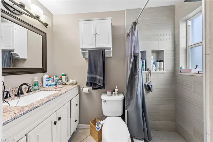 Bathroom featuring a shower with shower curtain, vanity, toilet, and tile patterned flooring