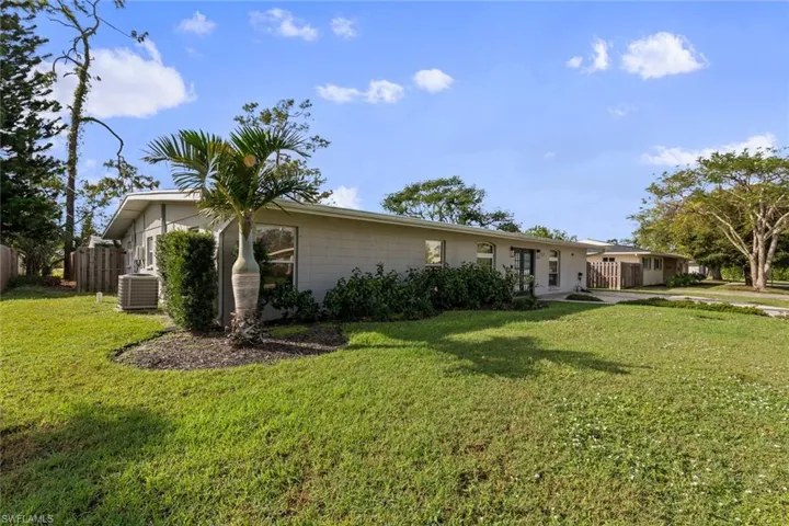 View of front of home with central AC unit and a front yard