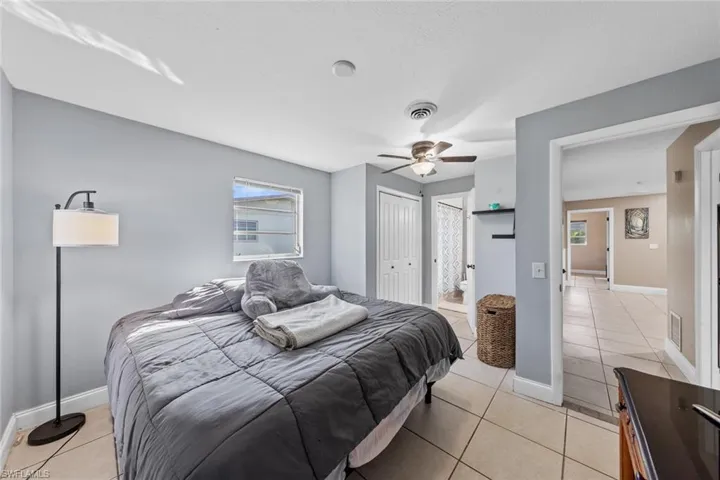 Bedroom with ceiling fan, ensuite bath, light tile patterned floors, and a closet