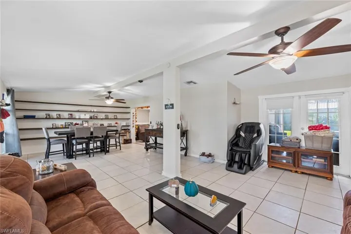 Living room featuring ceiling fan, french doors, light tile patterned floors, and beamed ceiling