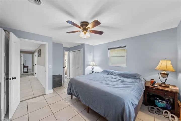 Tiled bedroom with ceiling fan and a closet
