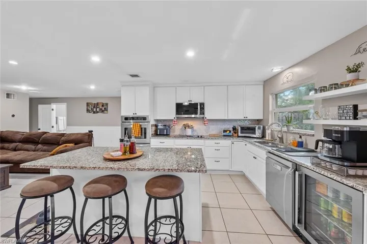 Kitchen with a center island, stainless steel appliances, wine cooler, a breakfast bar, and white cabinets