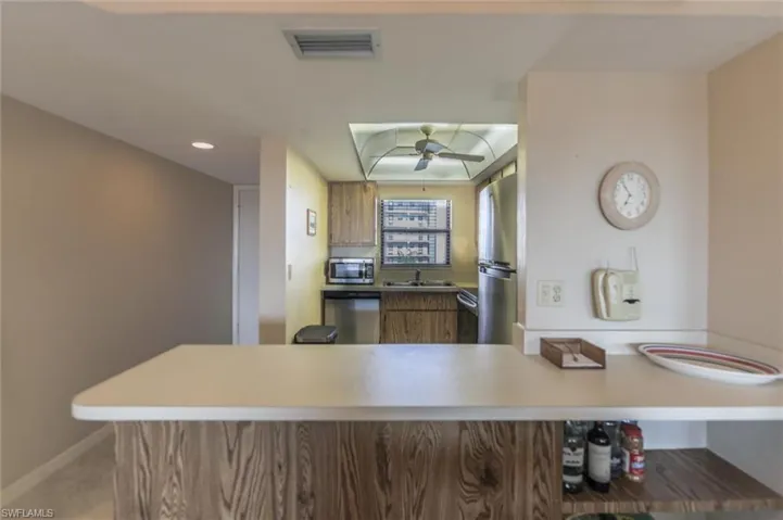 Kitchen with ceiling fan, kitchen peninsula, stainless steel appliances, and sink