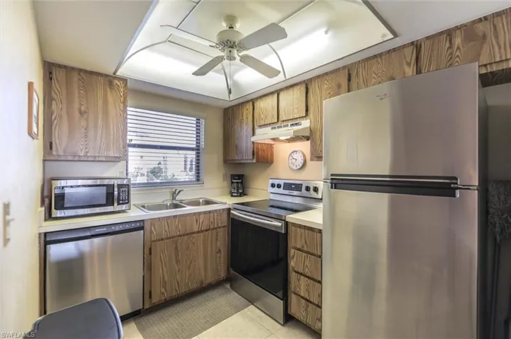 Kitchen featuring appliances with stainless steel finishes, sink, ceiling fan, and light tile floors