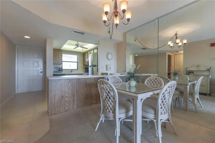 Dining space featuring ceiling fan with notable chandelier and light tile floors