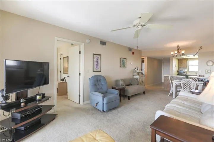 Carpeted living room with ceiling fan with notable chandelier