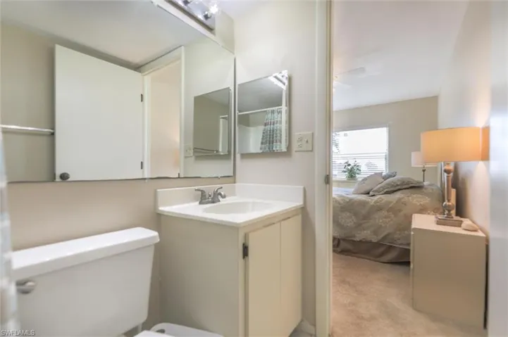 Bathroom featuring ceiling fan, toilet, and vanity with extensive cabinet space