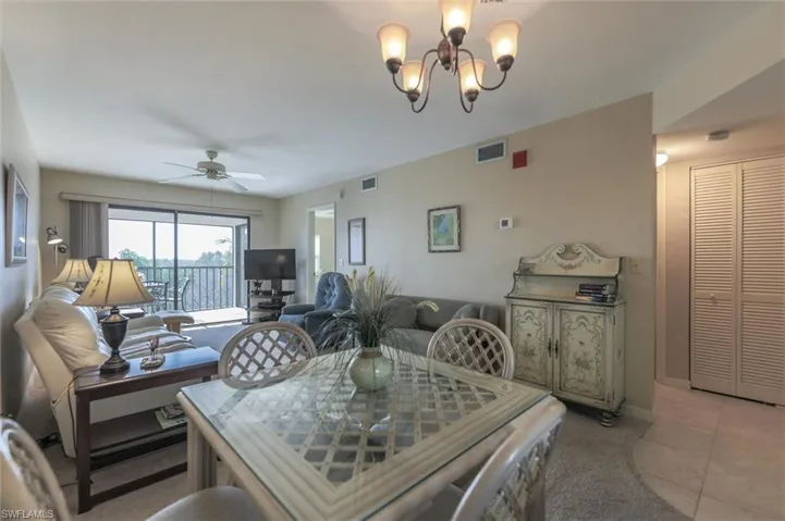 Tiled dining room with ceiling fan with notable chandelier