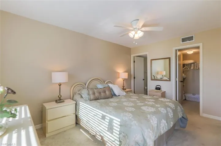 Carpeted bedroom with a walk in closet, a closet, and ceiling fan