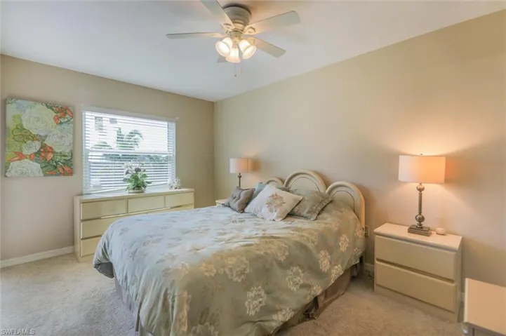Bedroom with ceiling fan and light colored carpet