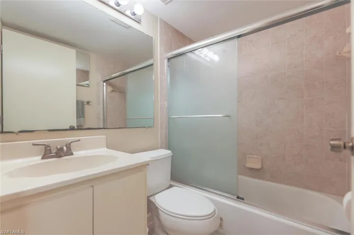Full bathroom featuring enclosed tub / shower combo, toilet, and vanity
